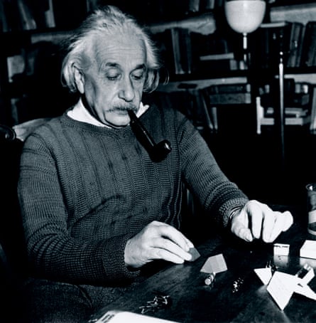 Albert Einstein smokes a pipe while solving a puzzle at his desk, the Princetone in February 1944