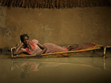 Nyapini Yiel, 23, lies in her bed surrounded by flood water.