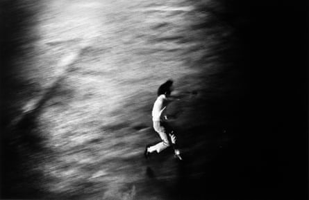 Black and white image of the blurry figure of a protester in Tokyo throwing a stone in protest against the Vietnam war