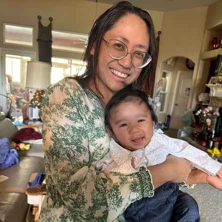 Woman in glasses holding baby, both smiling.