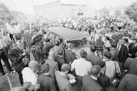 Newsmen and photographers surround a hearse bearing the body of George Lincoln Rockwell.