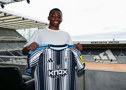 Bazoumana Toure poses for photographs holding a new strip during his media duties at St James' Park