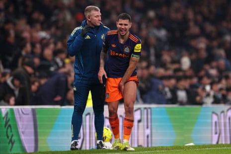 Bruno Guimaraes holds his hamstring while standing next to a physio during Newcastle's match against Tottenham