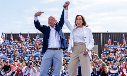 a man points to a woman on stage with a rally crowd in the background