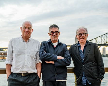 They stand shoulder to shoulder on a waterfront, with part of Sydney Harbour Bridge visible behind them