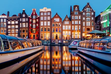 Amsterdam canal, boats and classic Dutch tall houses reflected in the water