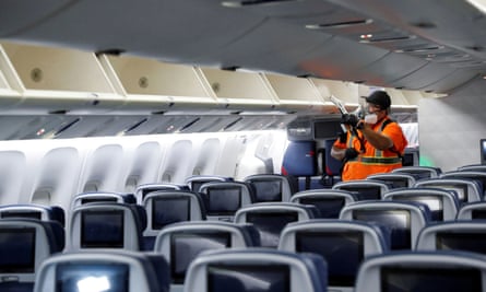 A Delta cleaning crew member in a respirator mask sprays disinfectant inside an aircraft cabin