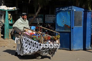 A man selling beauty items pushes his handcart through a street in Kandahar