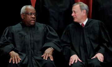Clarence Thomas and John Roberts in robes talking to one another