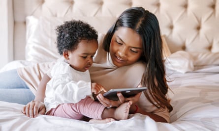 A mother and baby at home, looking at a tablet.