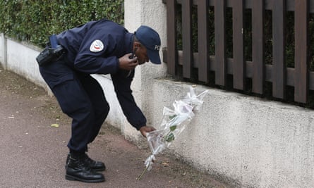 A French police officer lays flowers while paying tribute to his colleagues killed in a knife attack near their home in Magnanville.