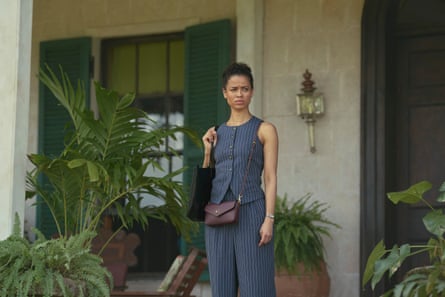 Gugu Mbatha-Raw next to large green plants in a trouser suit