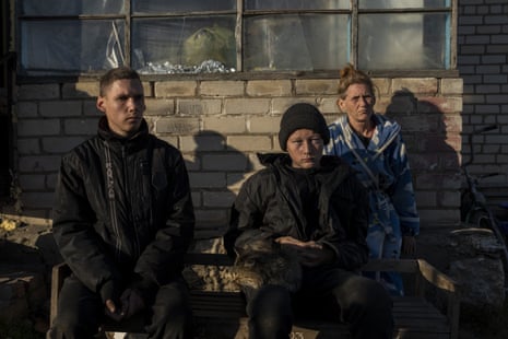 Alesha Babenko, 27, left, Vitaliy Mysharskiy, 14, centre, and family member Tanya Babii sit in the yard of the family house in the recently retaken village of Kyselivka, on the outskirts of Kherson.
