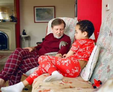 David and Macsen Lewis sitting on a sofa in their pyjamas. David appears to have a baby grey squirrel on his arm