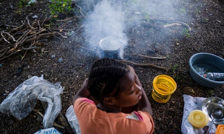 A woman cooks at the Hugo Chávez Square where she shelters from gang war violence in Port-au-Prince, Haiti, on 16 October.