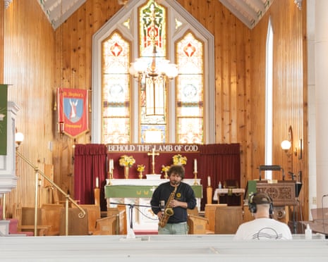 Man playing saxophone in church as another man in headphones faces him