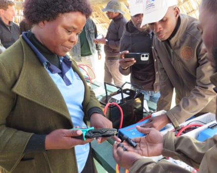 Mabel Nokhuthula Piki hold a pair of pliers during a demonstration next to what look like battery packs.