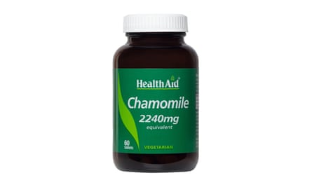 A dark brown glass bottle with a green label containing chamomile tablets