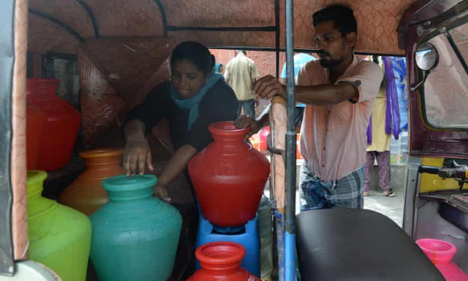 Residents arrange plastic pots filled with drinking water in an auto rickshaw at a distribution point in Chennai