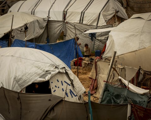 people stand among tents