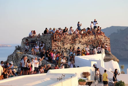 Crowds of tourists sitting on walls next to the sea