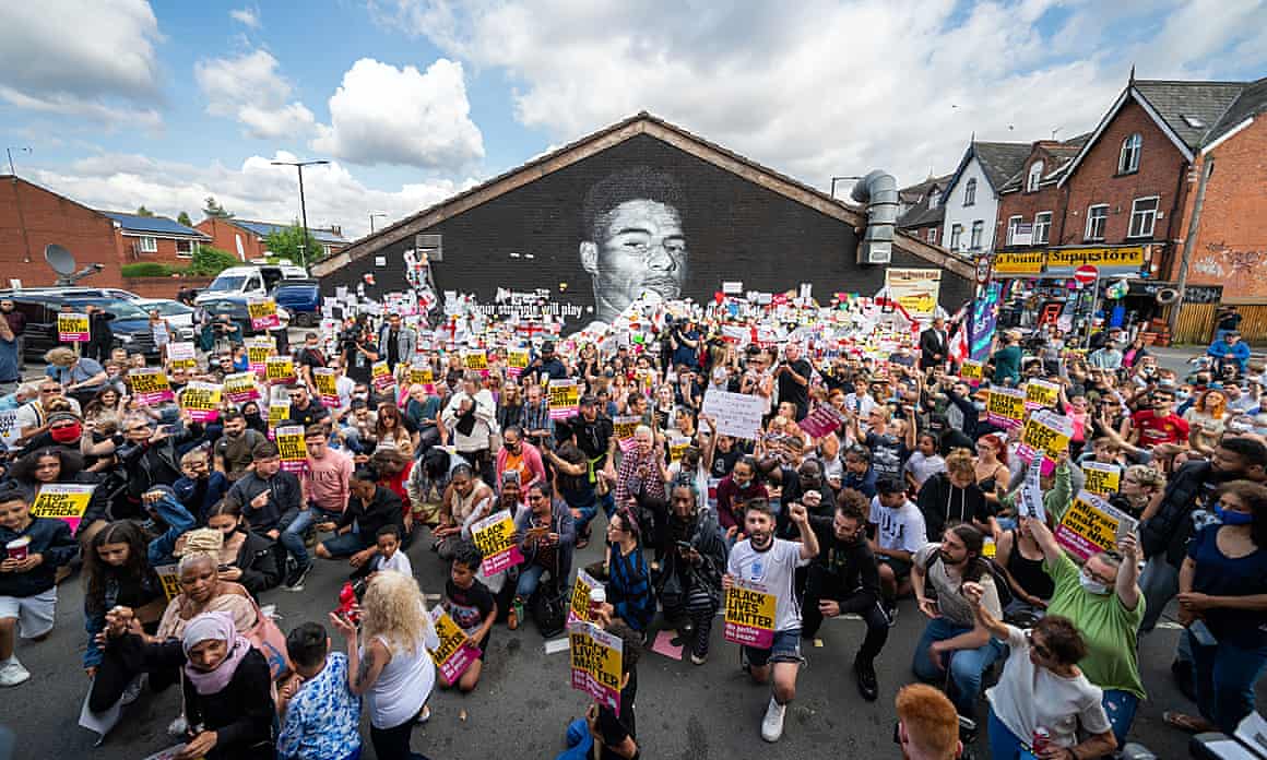People take the knee in front of a mural of Manchester United striker and England player Marcus Rashford in Withington, Manchester.