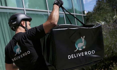 A Deliveroo worker loads his bicycle after making a delivery in London