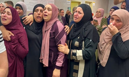 Women wearing headscarves crying and with arms around each other 