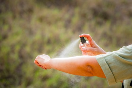 Woman spraying mosquito insect repellant on her arm.