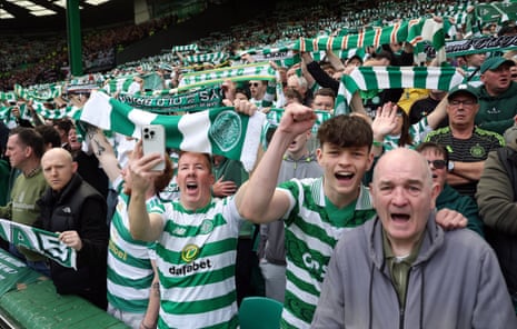 Celtic fans hold their scarves aloft in the stands.