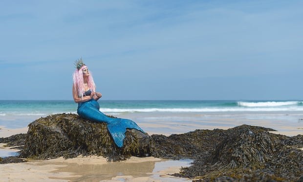 Laura Evans in mermaid tail on a rock