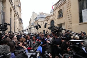 Two men surrounded by journalists and microphone booms give a press conference in a street