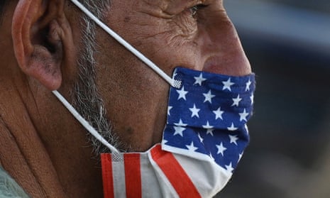 A man wears an American flag face mask on a street in Hollywood, California, after the indoor mask mandate returned to Los Angeles. With the Delta variant pushing US Covid cases back up, fully vaccinated people are wondering whether they need to start masking indoors again. Covid vaccines remain extremely effective against hospitalization and death.