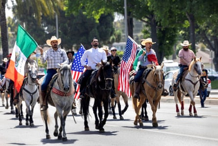 horse riders carry mexican and us flags