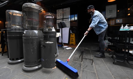 Staff member sweeps the footpath in front of a restaurant