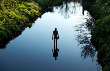 A metal sculpture of a man standing in a river