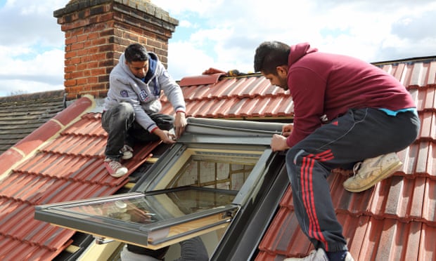 builders installing a roof window on a pitched tiled roof in South London