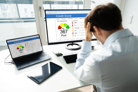 a man holds his head in despair after looking at a computer screen showing a low credit score