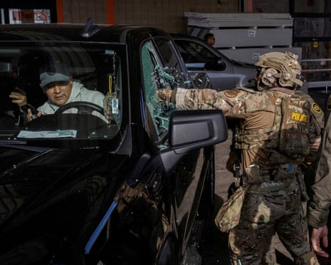 Federal agents smash a car window while trying to detain a man during an immigration raid in Chicago, Illinois, on 17 December