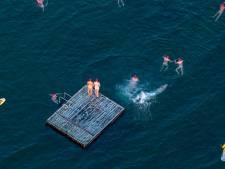 Aerial focusing on two nude persons standing on a pontoon in the river