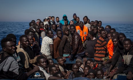 migrants wait to be rescued from a small wooden boat