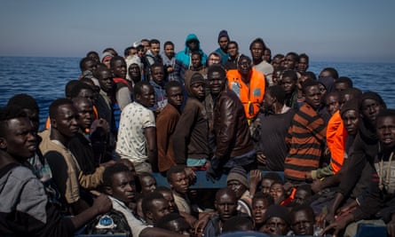 Refugees and migrants wait to be rescued from a boat in the Mediterranean
