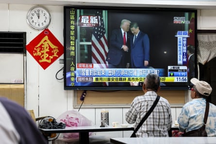 People watch a news programme in Taipei showing the meeting between Trump and Xi