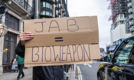 A protester holds a sign saying “Jab = Bioweapon” outside Parliament, London, 13 December 2021.