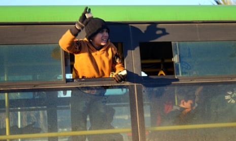 A boy waves from an evacuation bus in Aleppo.