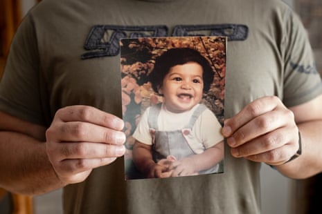 Peter holds a photograph of himself as a baby, before he was stolen from his mother in Chile
