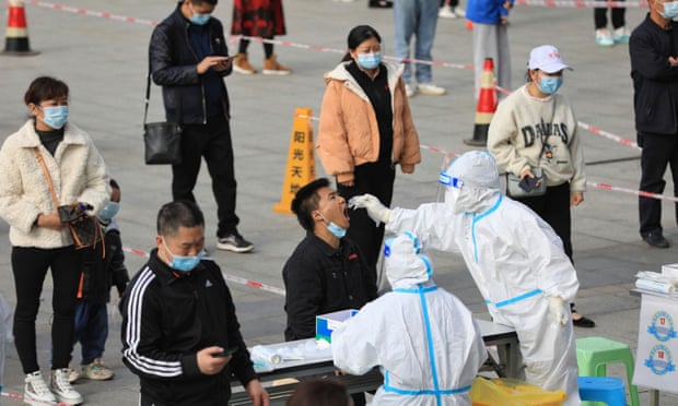 People queue in front of health workers in protective suits at a mass Covid testing site in Guizhou province, China