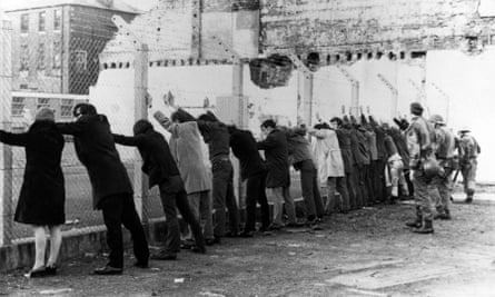 A scene from Derry in 1971 showing people being lined up against a wire fence by british soldiers