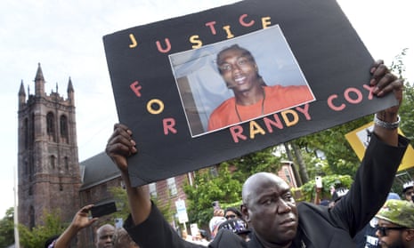 Man holding a banner that reads 'Justice for Randy Cox'