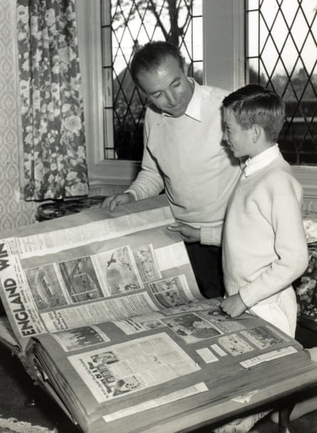 Footballer Stanley Matthews and his son smile looking at his football scrapbook